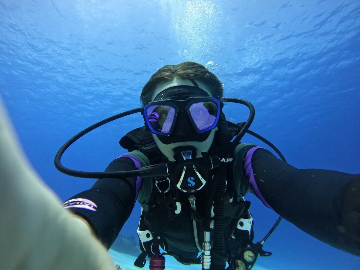 A person wearing scuba gear poses for an underwater photo.