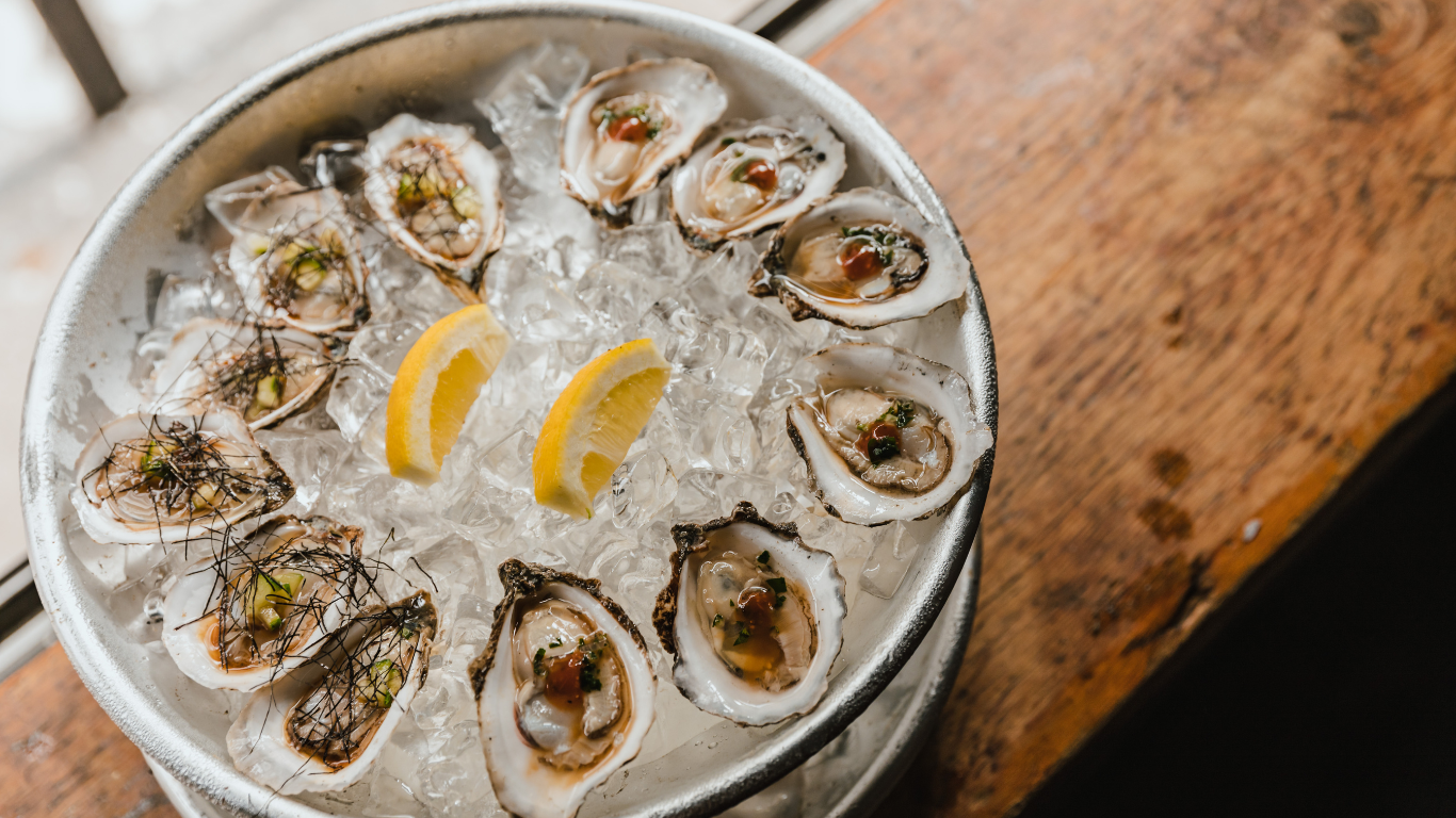 A plate full of ice and ringed with oysters on the half shell.