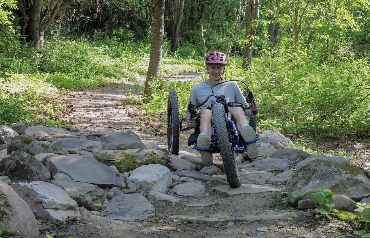 A person on an adaptive bike riding down a trail.