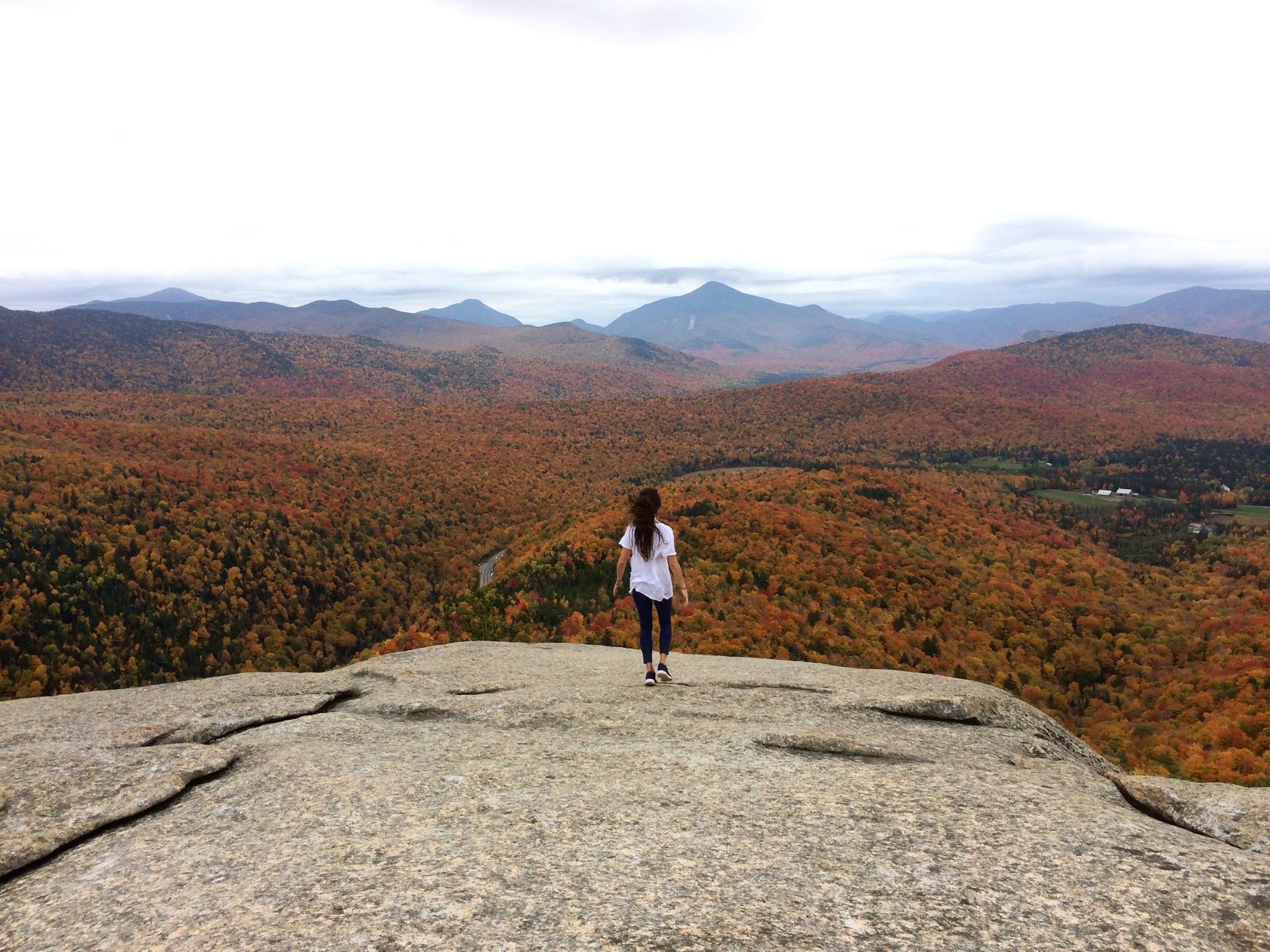 Woman on rocky mountain top looking at Adirondacks.