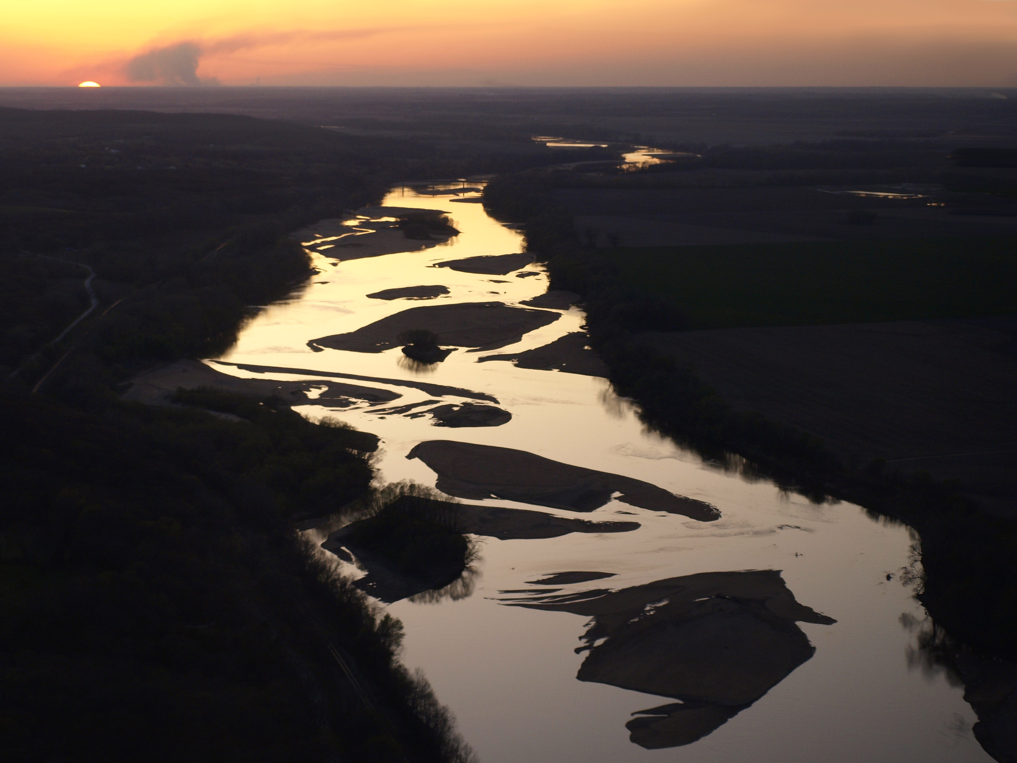 The sun sets behind a winding river.