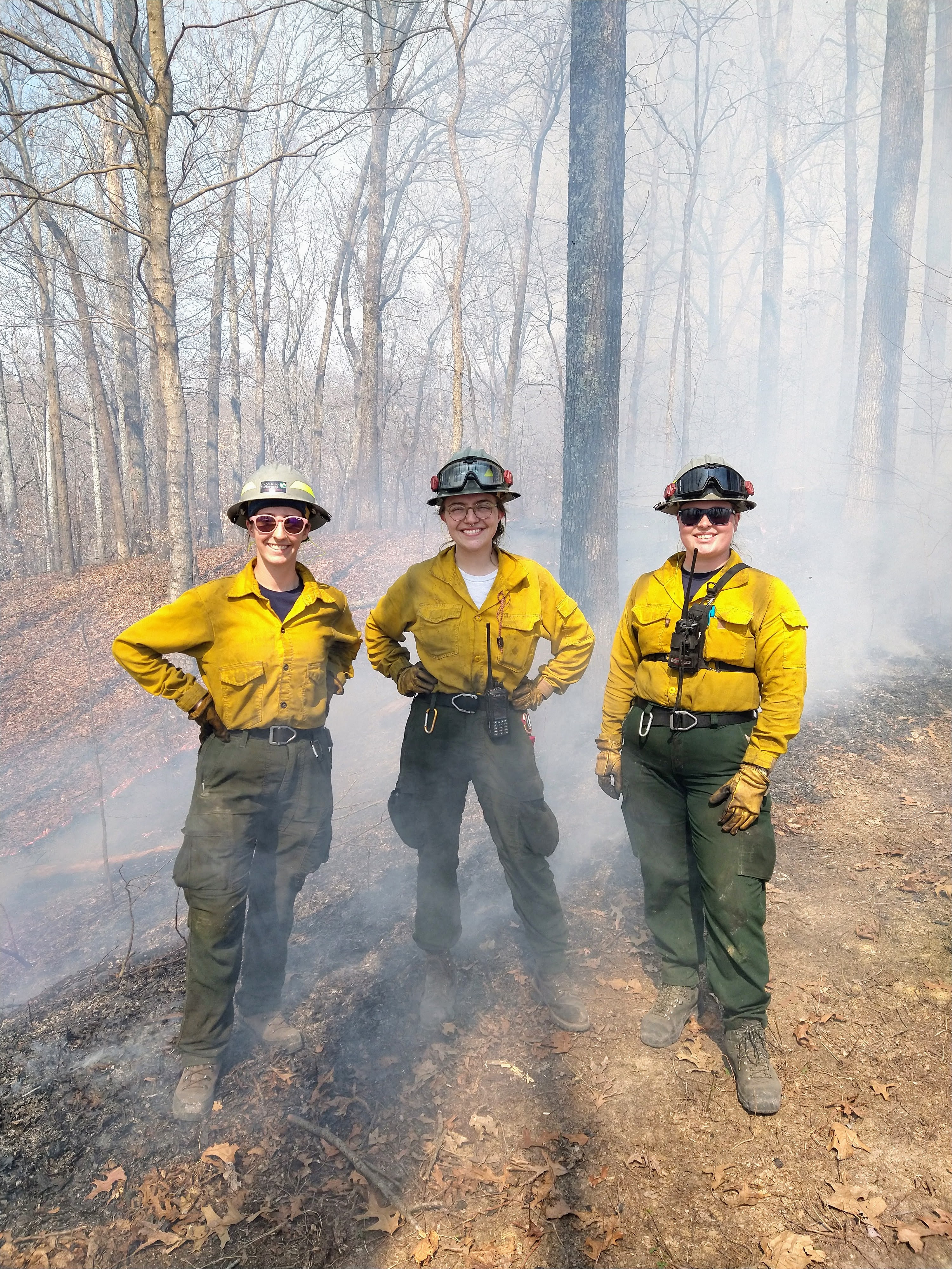 Three TNC staff members standing outdoors during a prescribed burn.