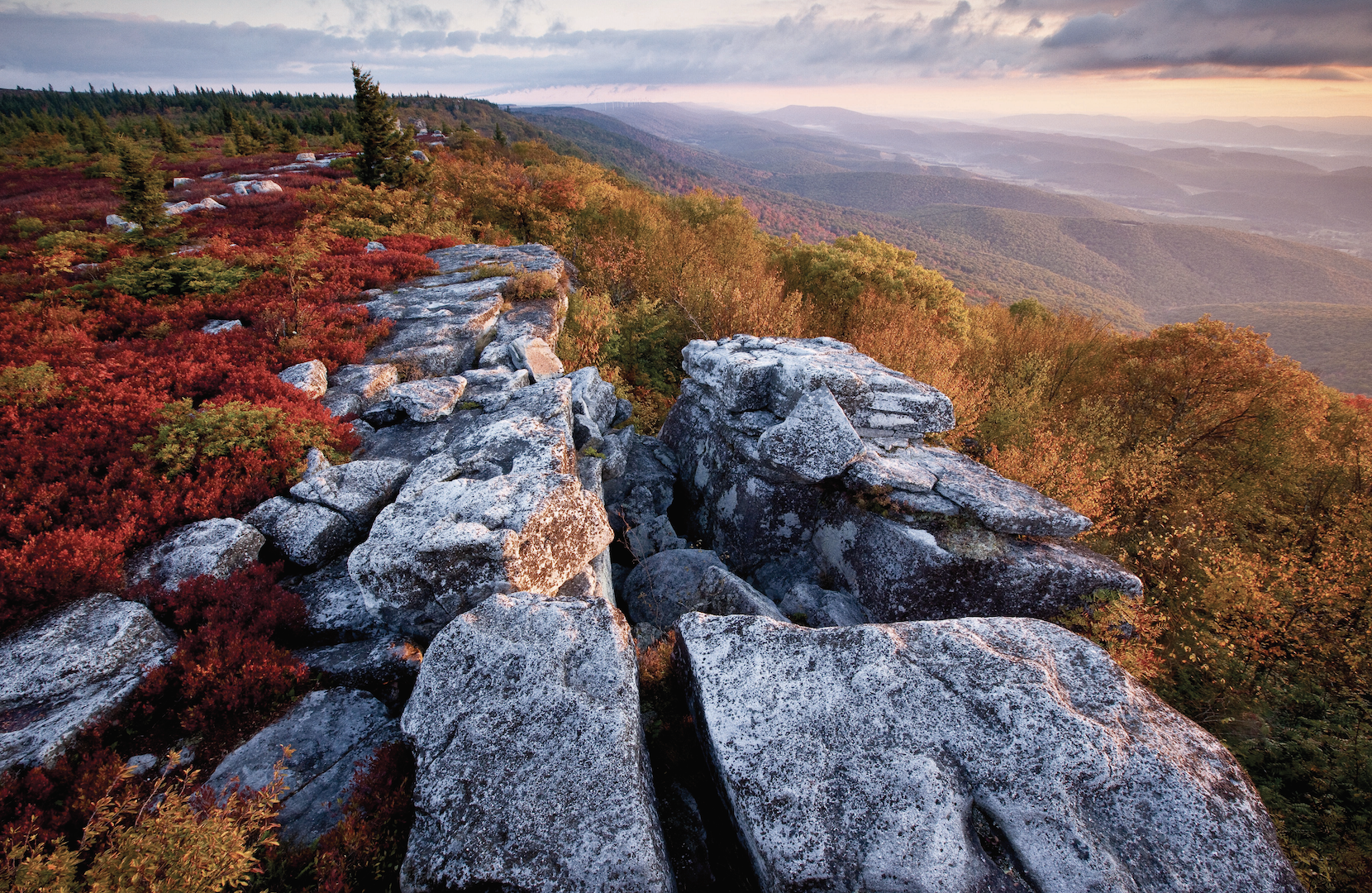 The sun rising over a rocky cliff face.