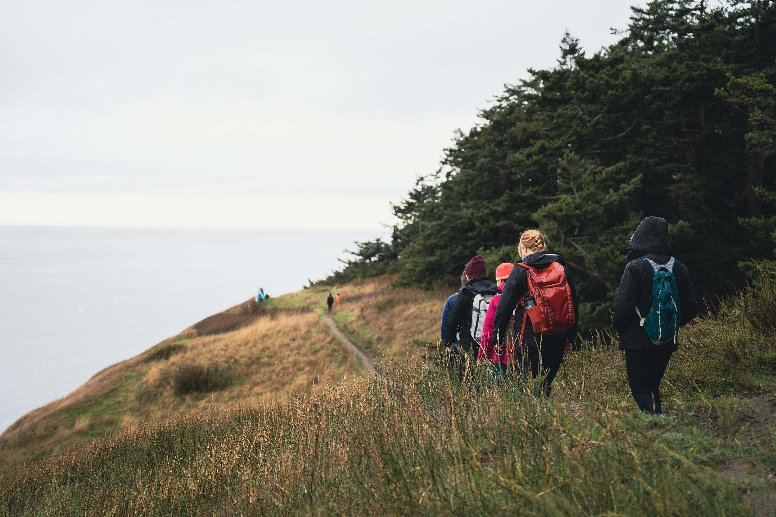  Several people hike along a narrow trail at the edge of a bluff.