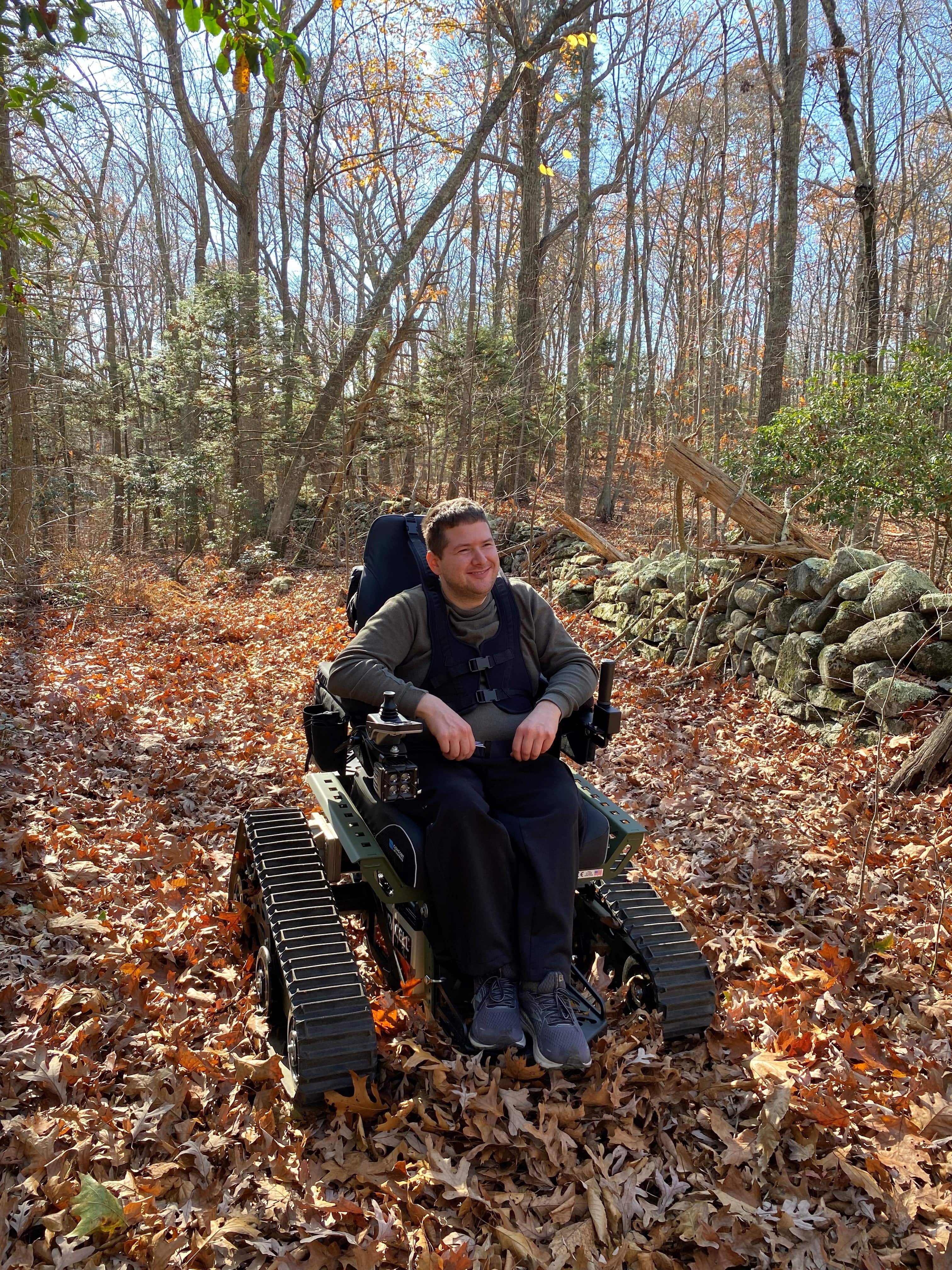 A person in a wheelchair is surrounded by woods.