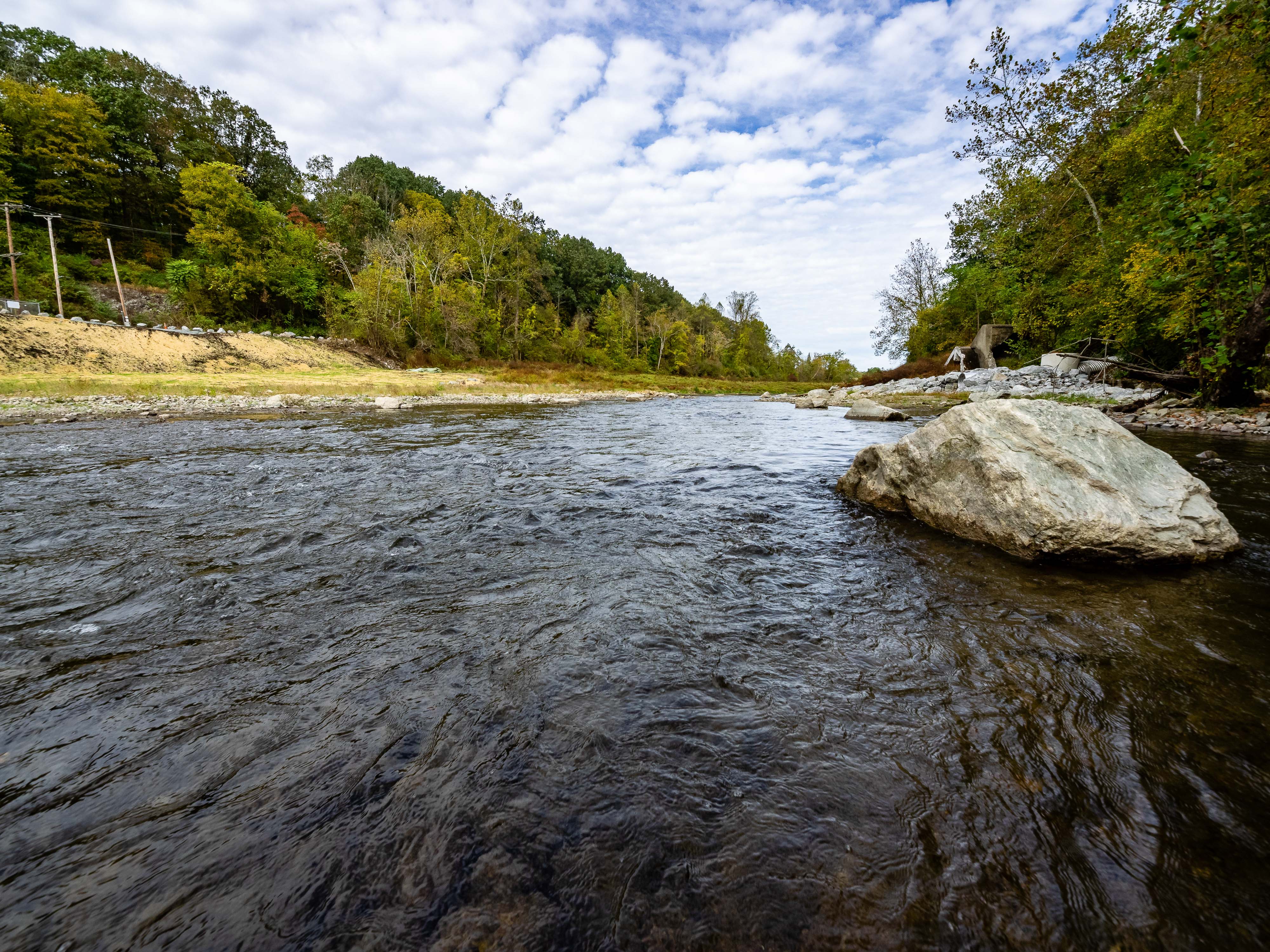 A wide river flows between tree lined banks.