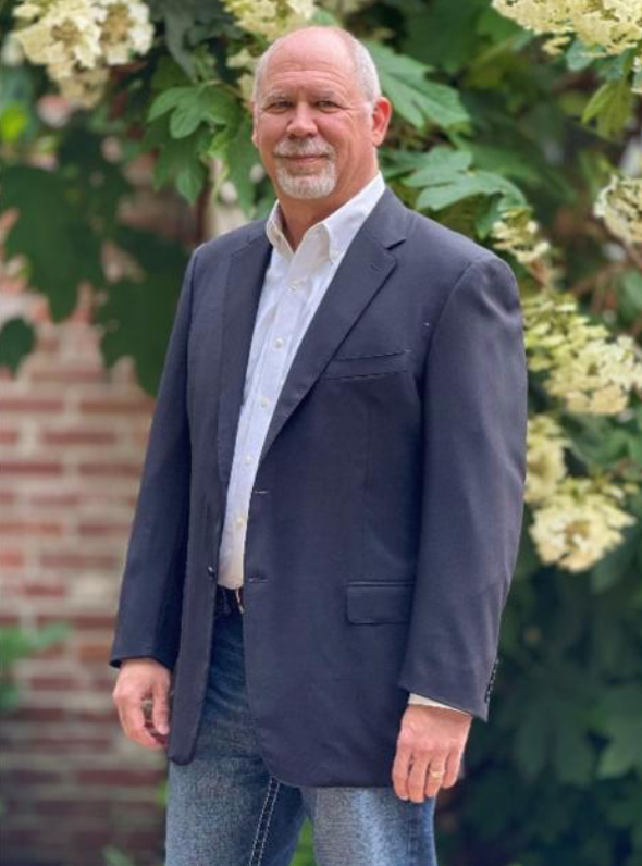 Douglas Swink wears a white collar shirt and a navy blue coat.