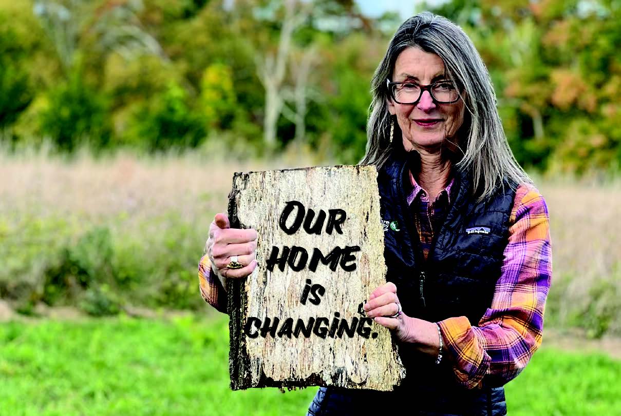 A woman holding a sign poses for a picture.