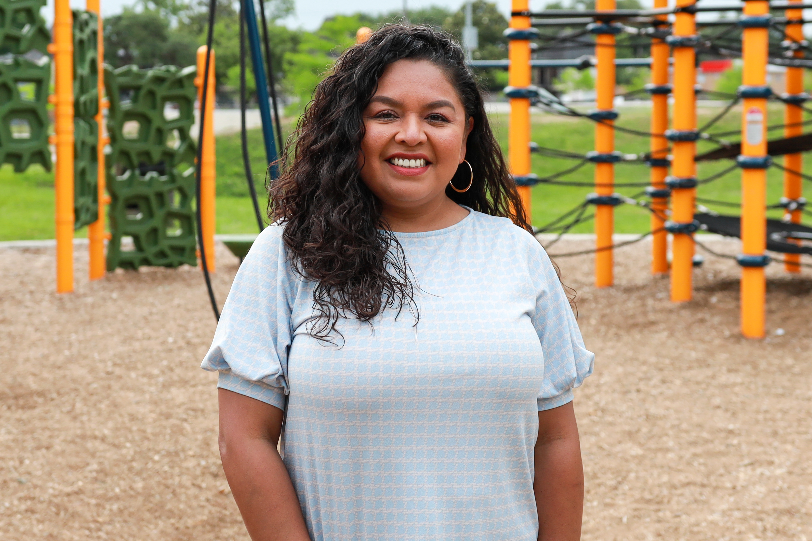 A woman stands in front of a playground.