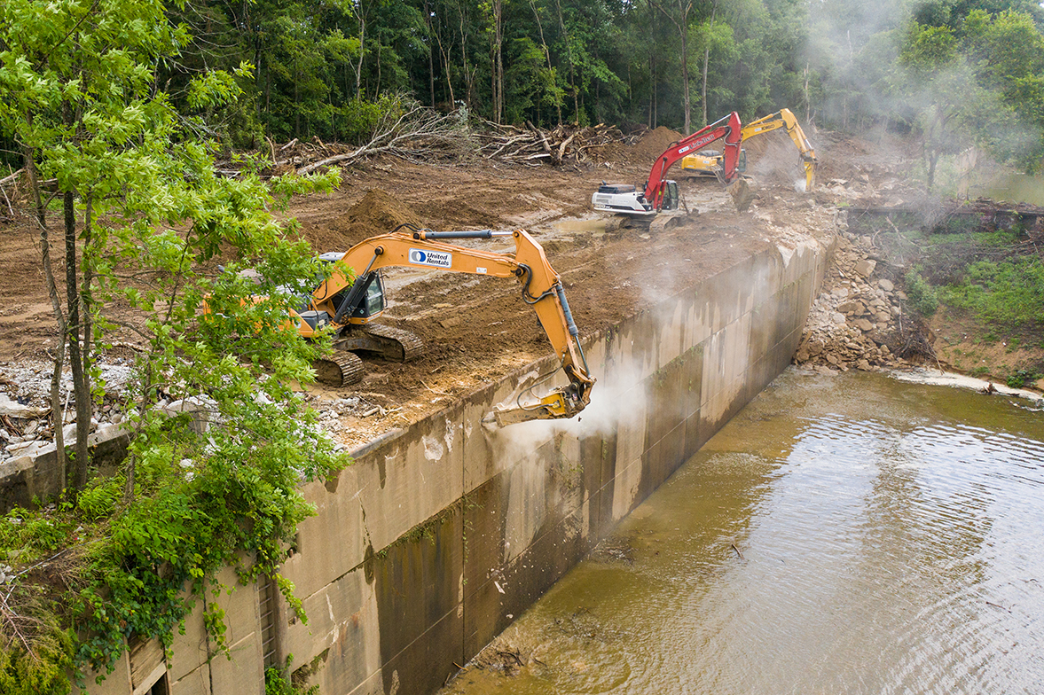 Three backhoes dismantle an aging dam.