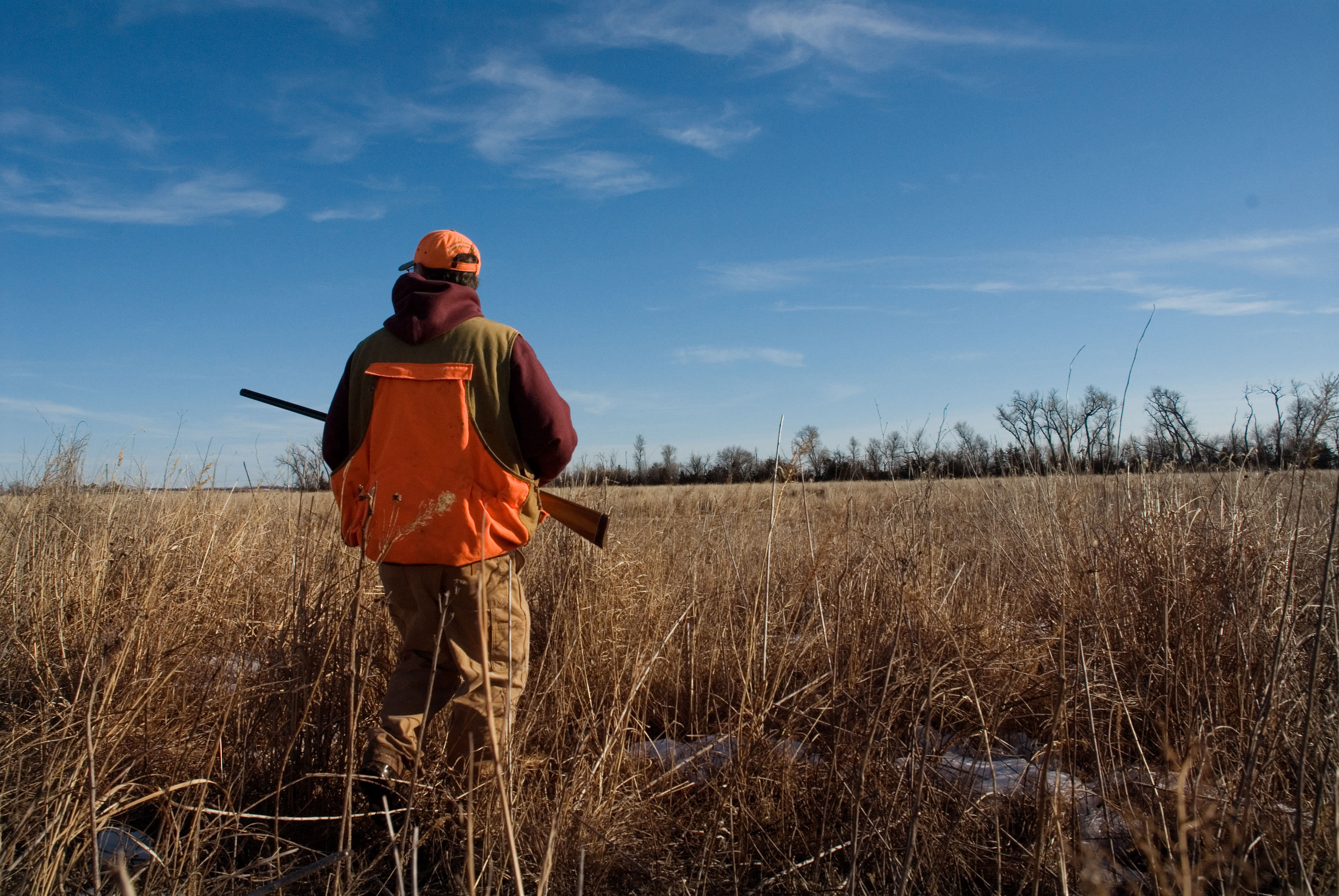 A hunter wearing a blaze orange cap and vest.