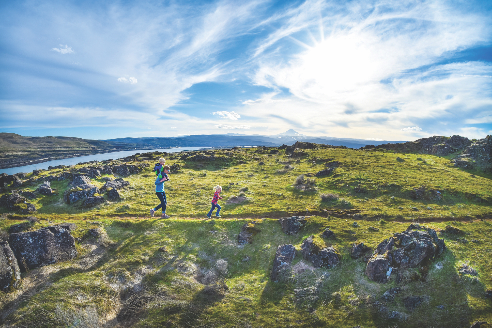 A dad and two kids walking on a trail.