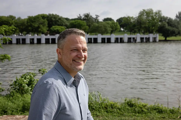 James McGuire stands in front of a body of water and smiles.