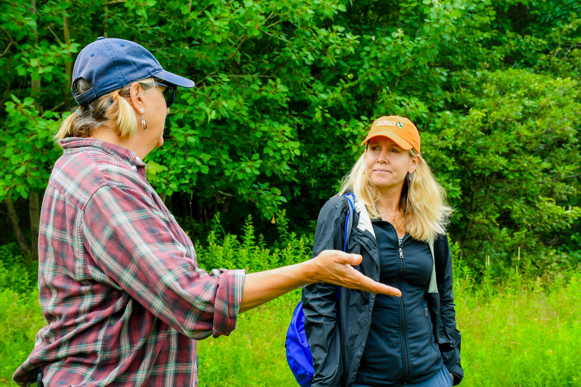 A person with their back to the camera talks to someone to their right.