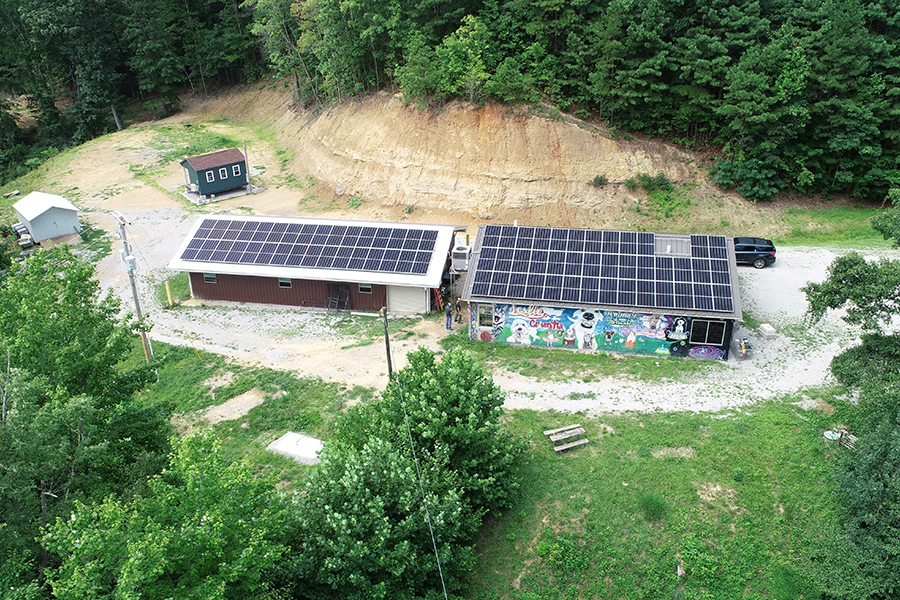 An animal shelter in a forested area has a roof covered in solar panels. 