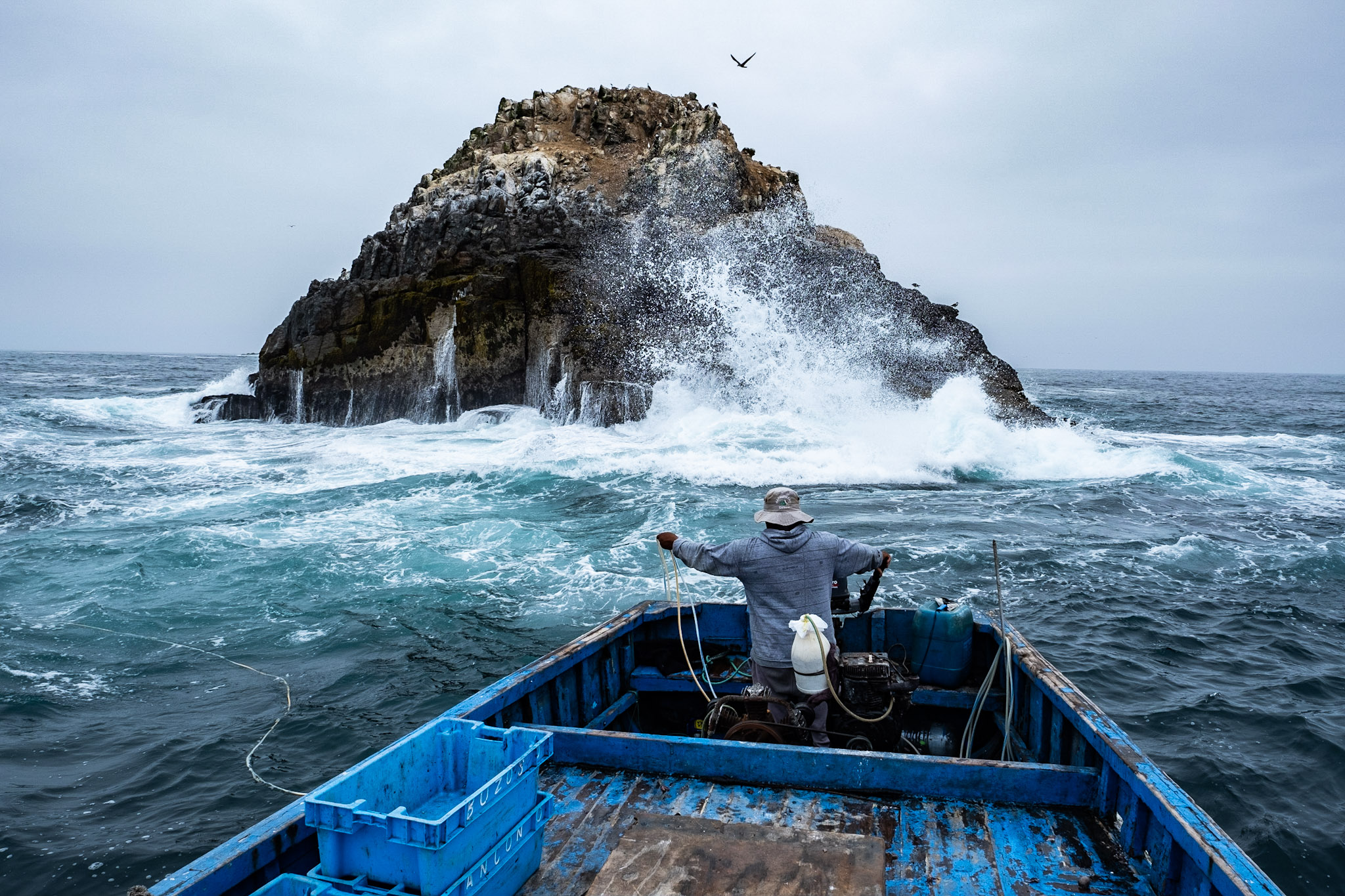 A person on a fishing boat near a small island.