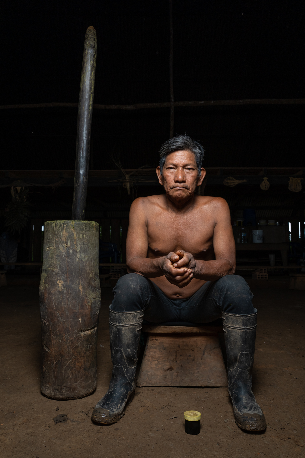 A man sitting on a bench, holding a large axe, with a focused expression on his face.