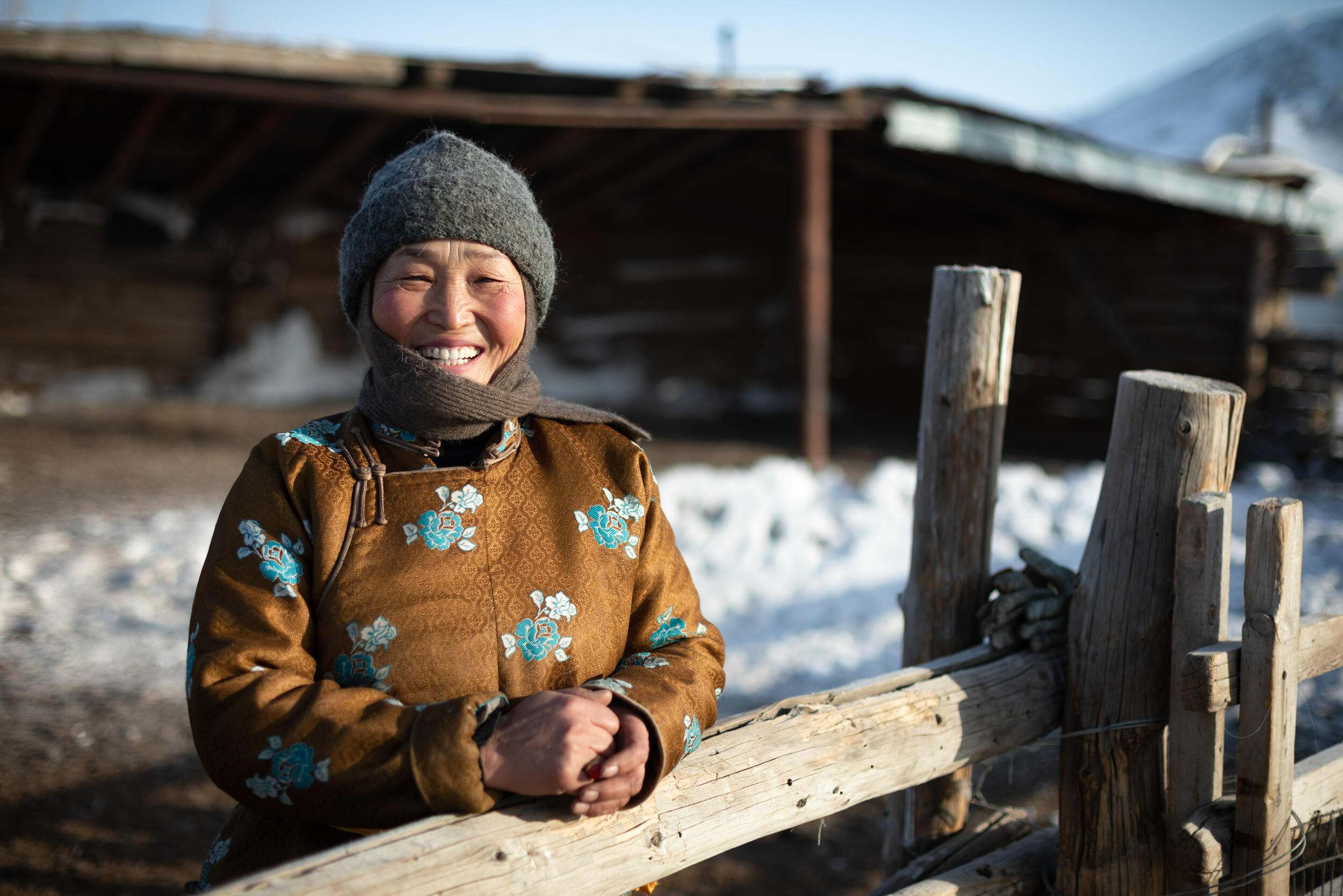 Female herder standing by fence, Mongolia.