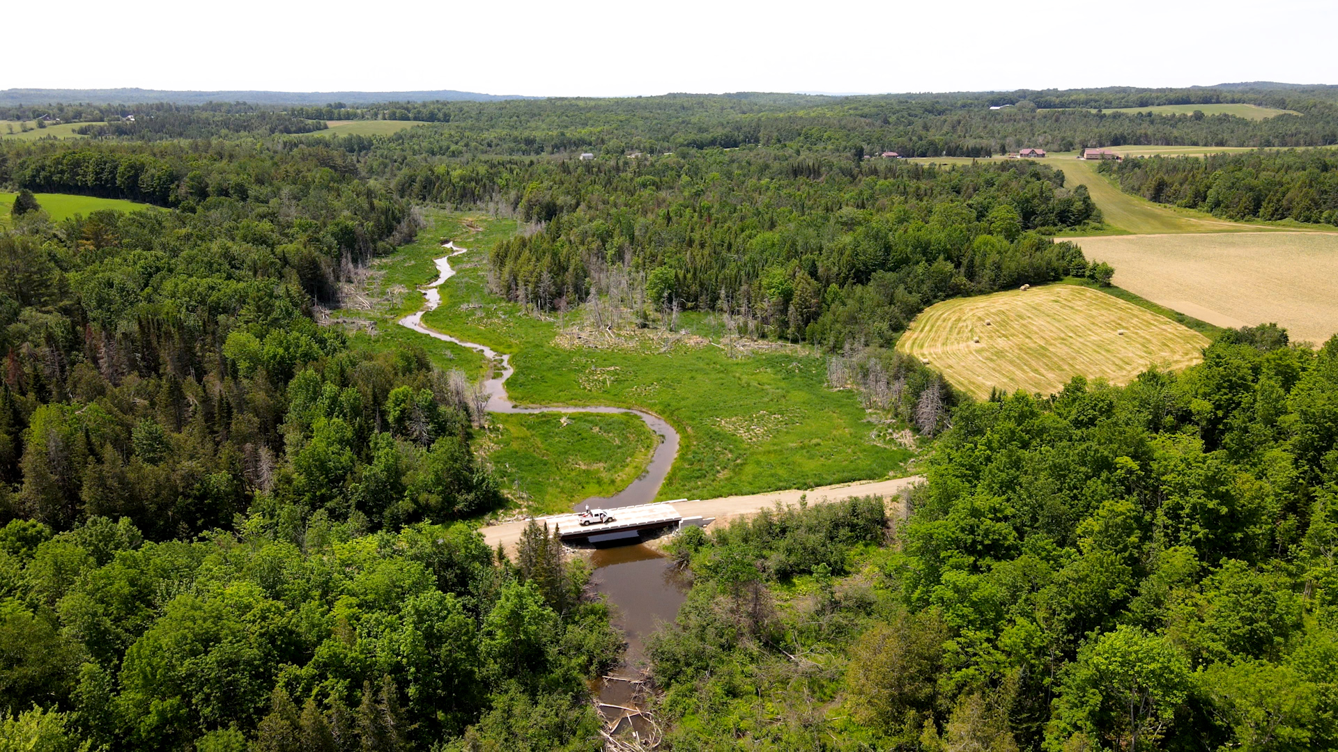 Aerial view of a new bridge over a stream in a field.