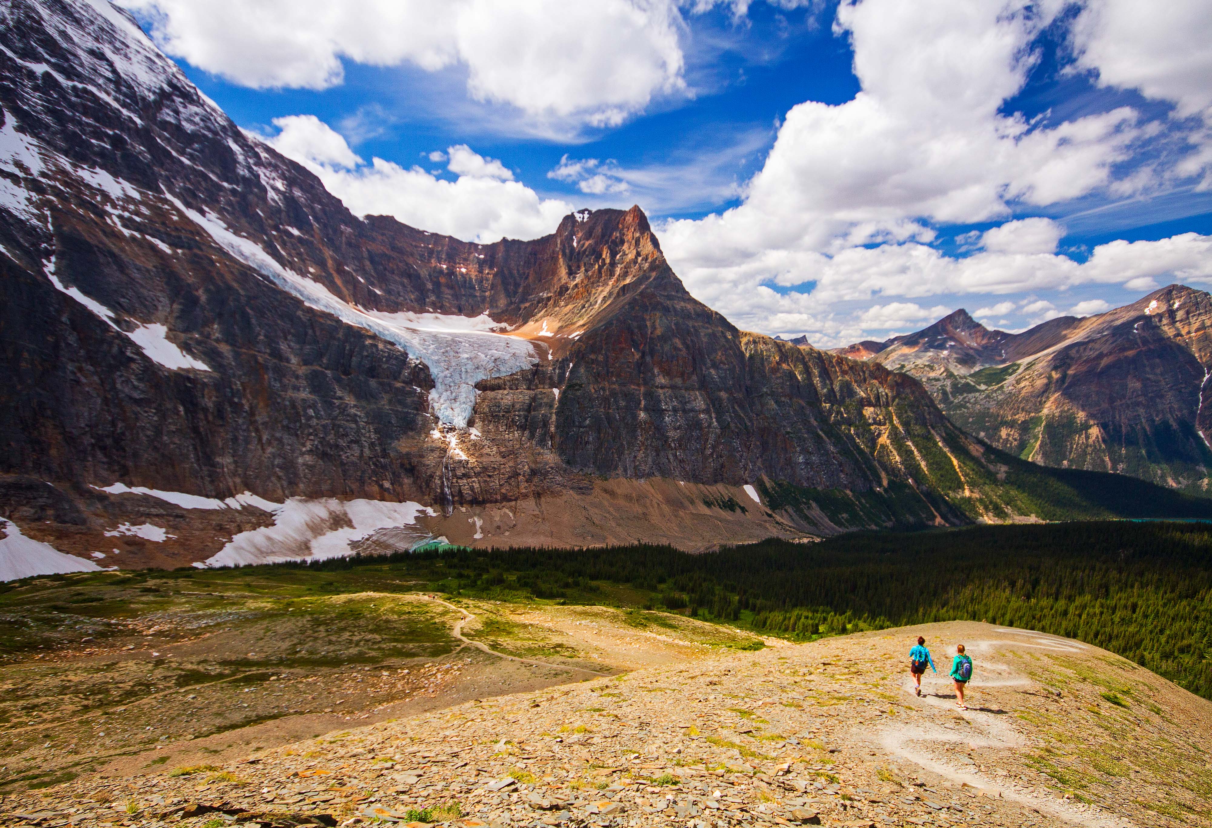 People hiking at the base of mountains. 
