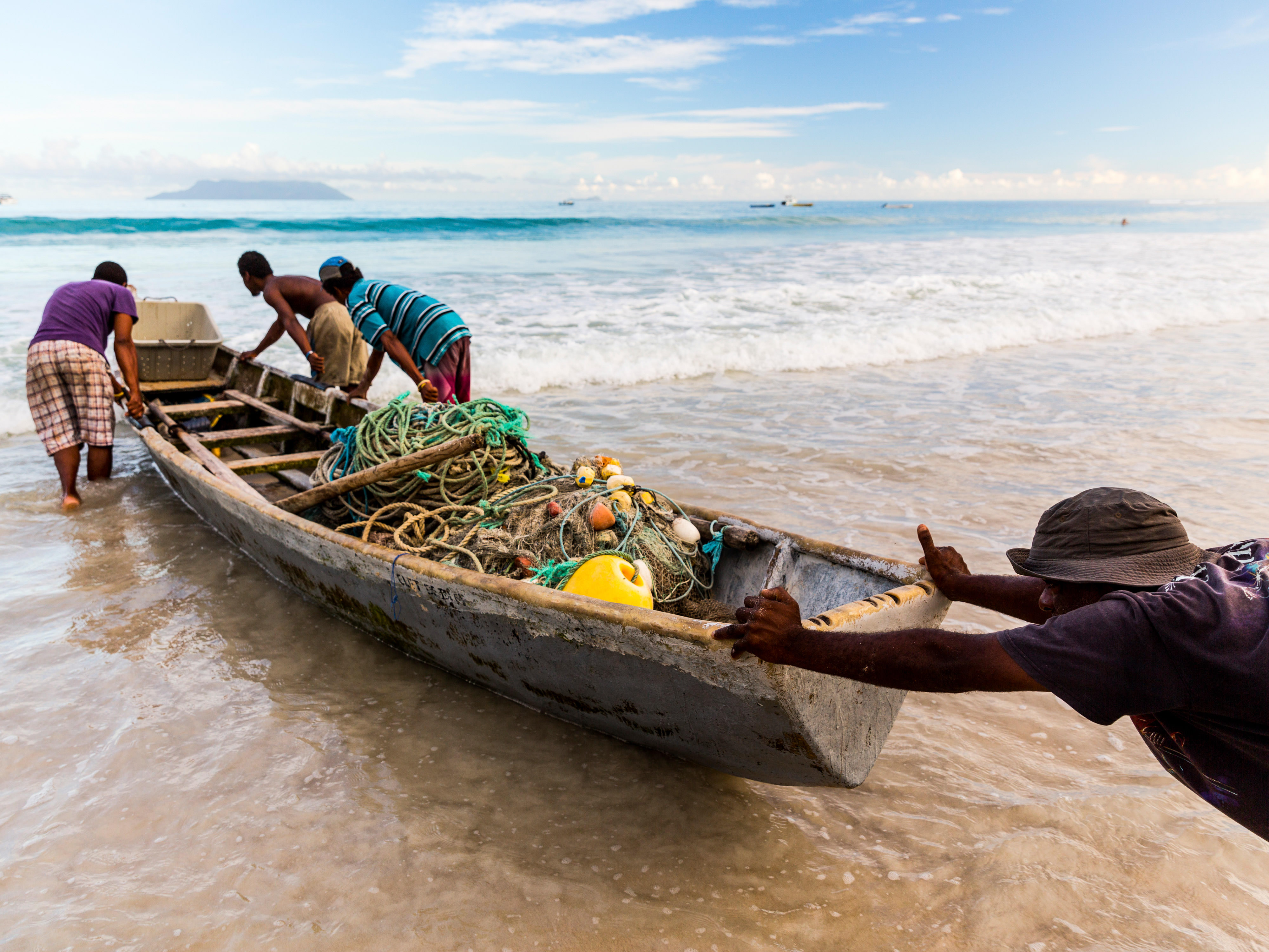 Fishers in Seychelles push their boat out to sea.