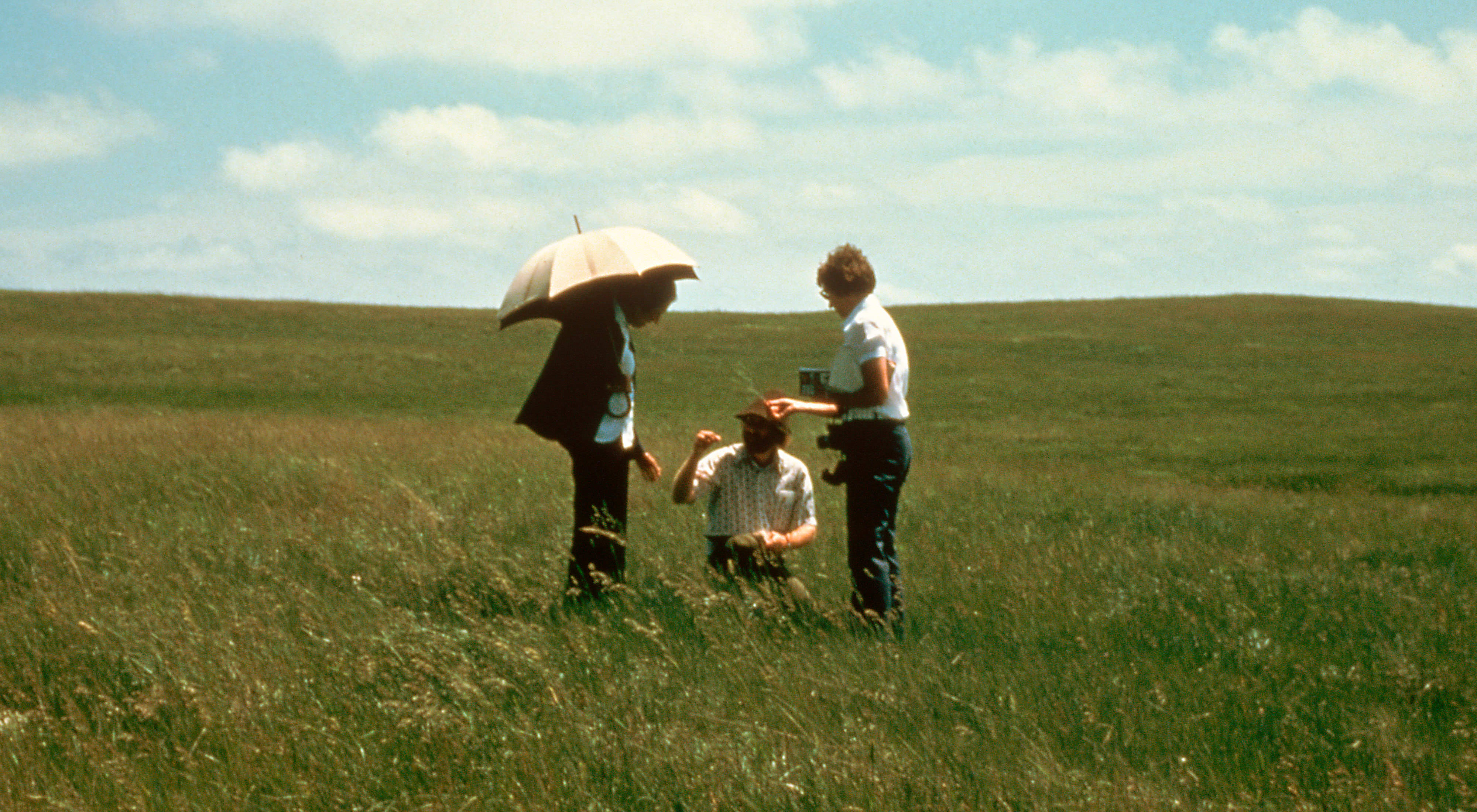 Three people standing in a prairie.