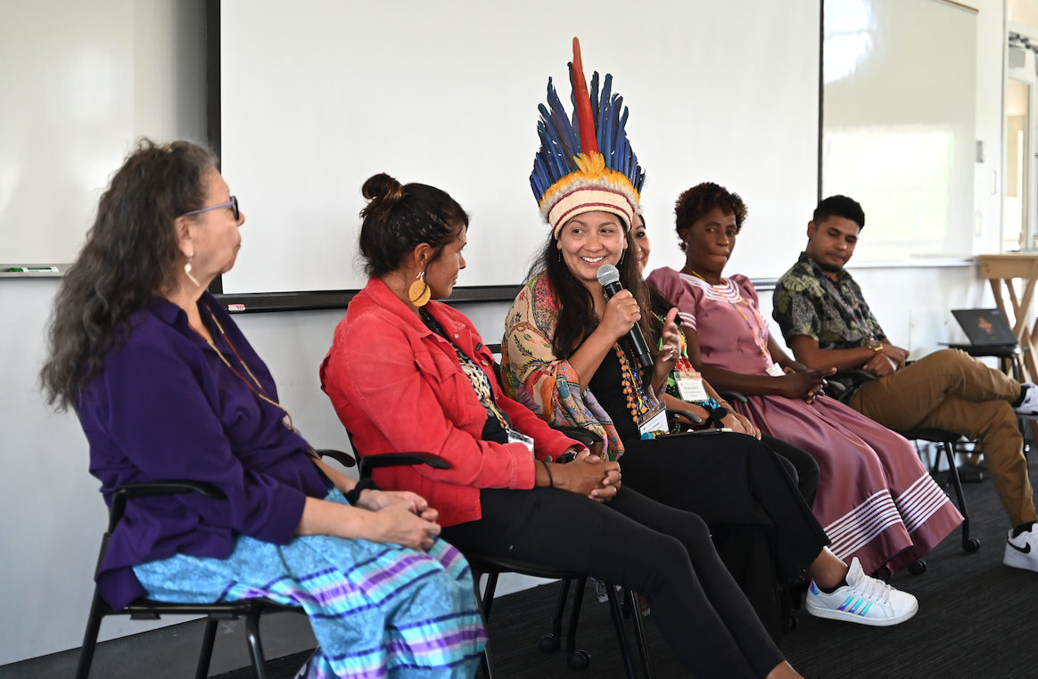 Four women seated in a panel with one holding the mic.