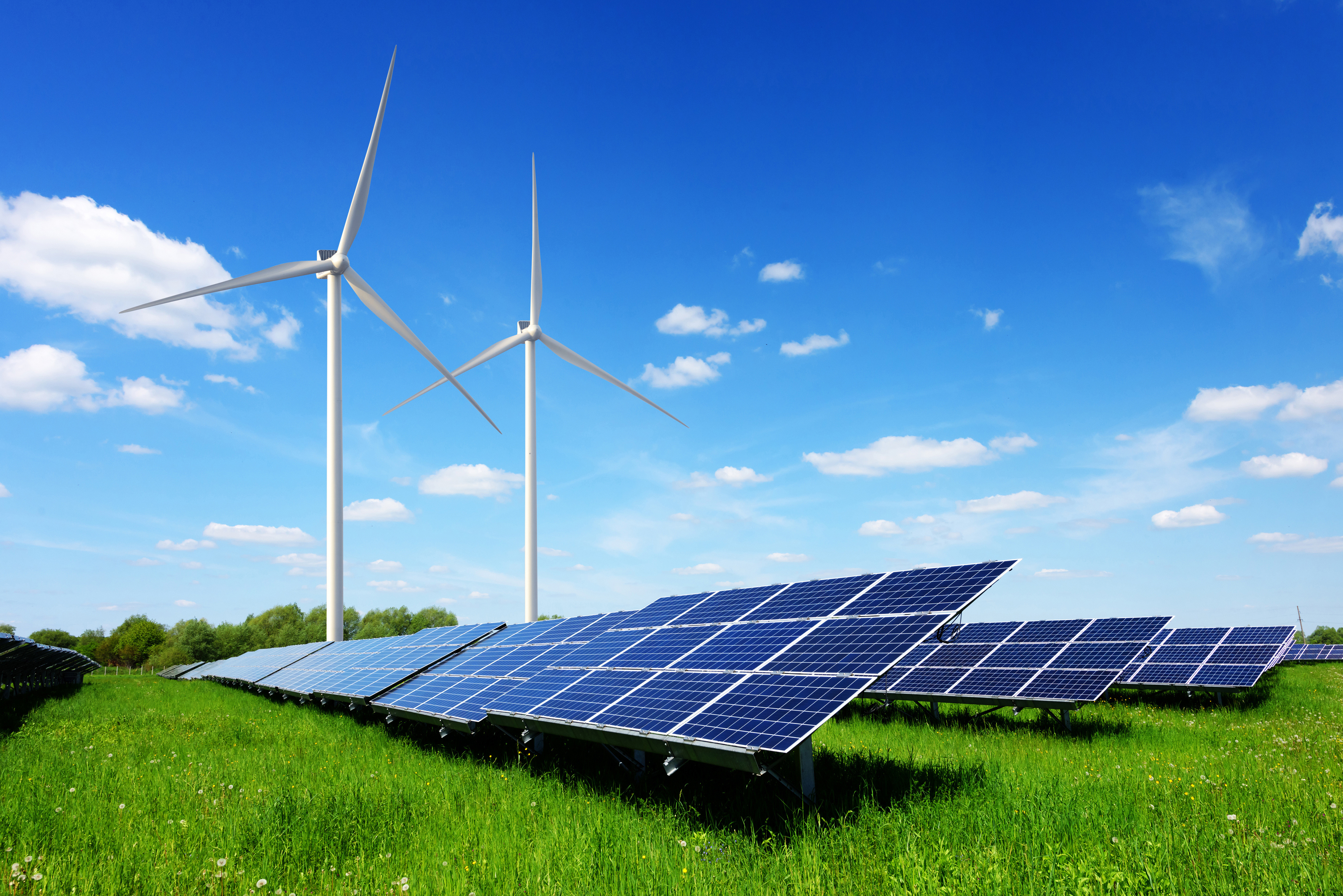 Solar panels and wind turbines in a green field. 