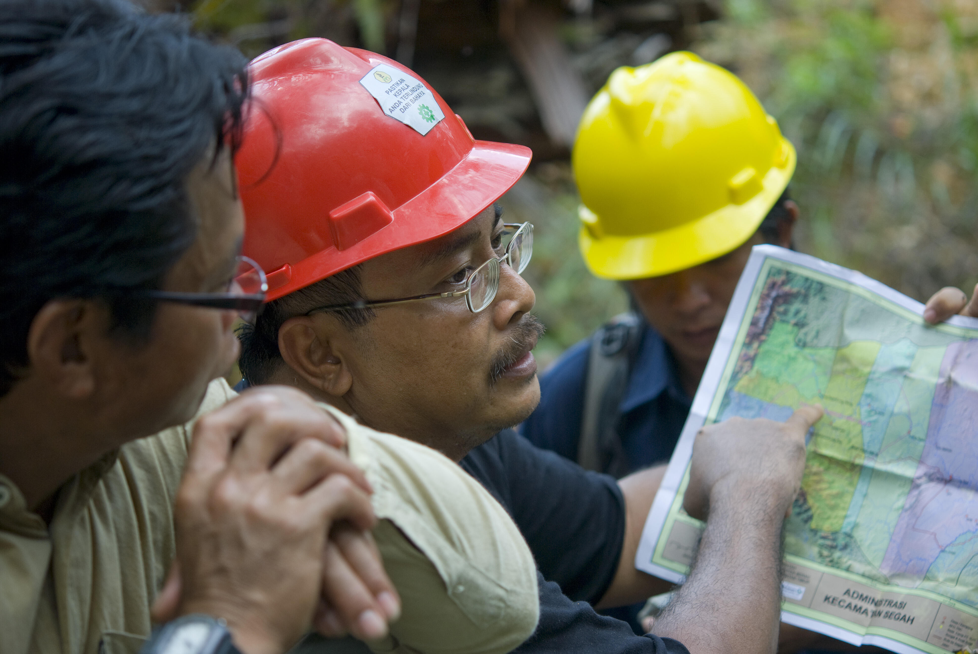 A group of people in construction gear stand around documents 